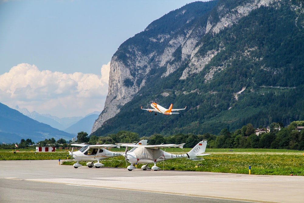 two white helicopters on road viewing mountain under blue and white skies during daytime