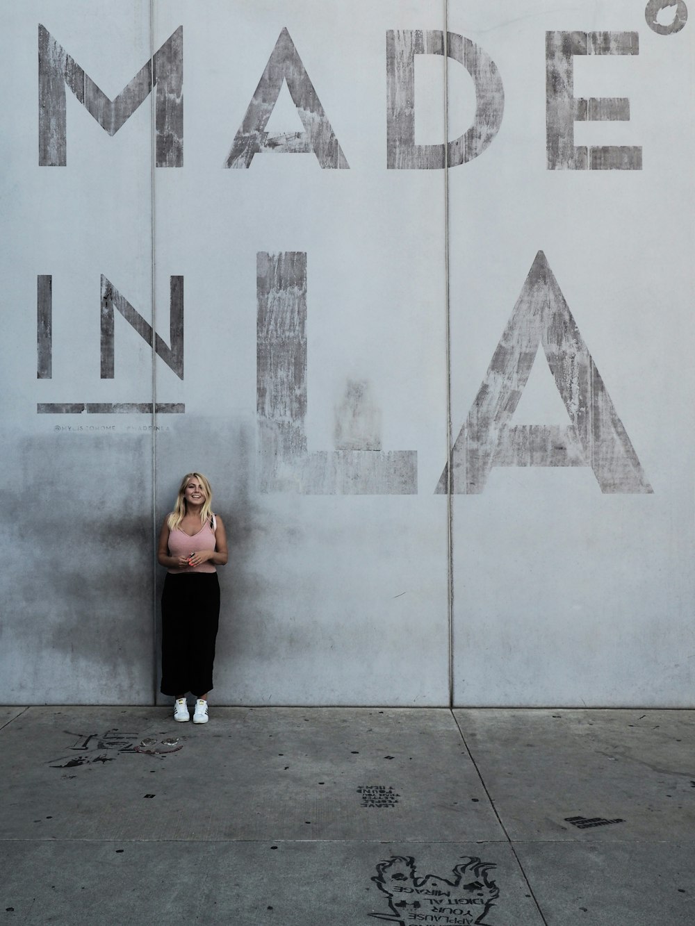 mulher em pé contra a parede com marca made in LA