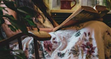 A cozy corner with botanical prints on the wall and a person reading a plant care book while sipping tea.