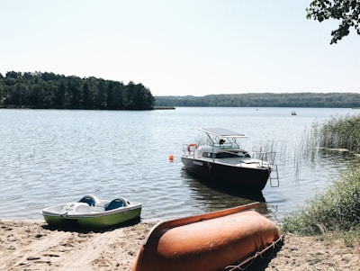 A scenic view of a calm lake with several jet skis lined up along the shore ready for rental.