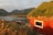 Smiling homeowner standing proudly in front of their newly finished rustic cabin by the sea in Homer, Alaska.