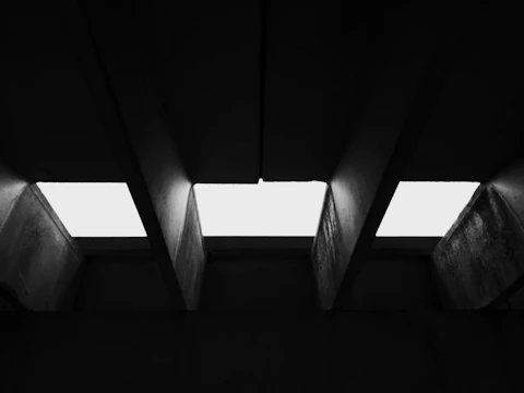 Black-and-white photo of Kinshasa’s raw concrete buildings with sharp geometric shadows.