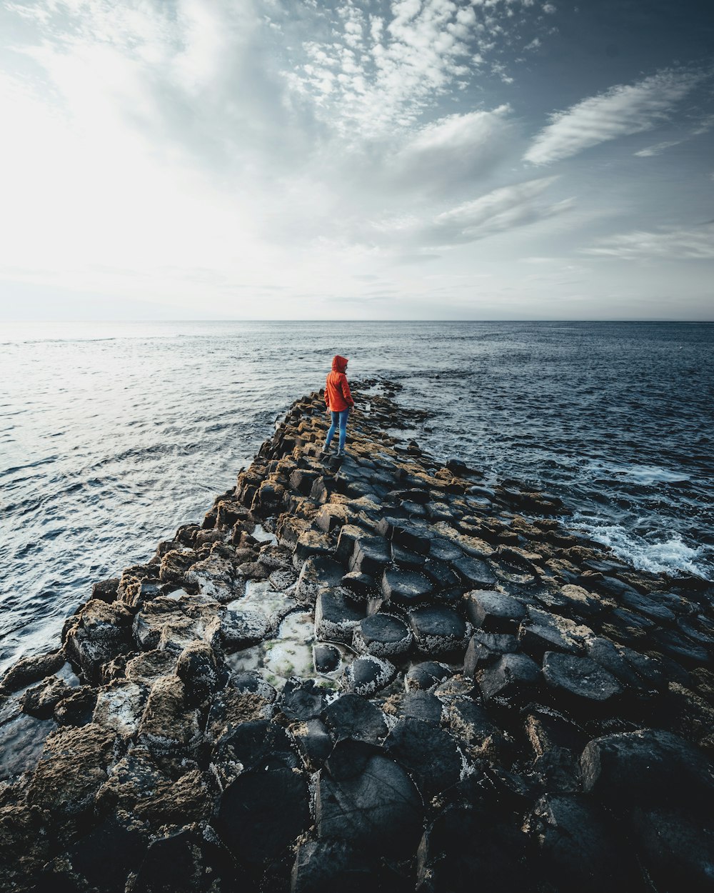Una persona in piedi sul bordo di un molo vicino all'oceano