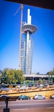A tall telecommunications tower under construction with workers and cranes.