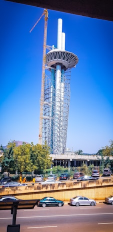 A tall telecommunications tower under construction with workers and cranes.