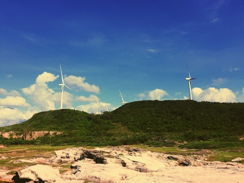 A wind turbine farm on a green hillside.