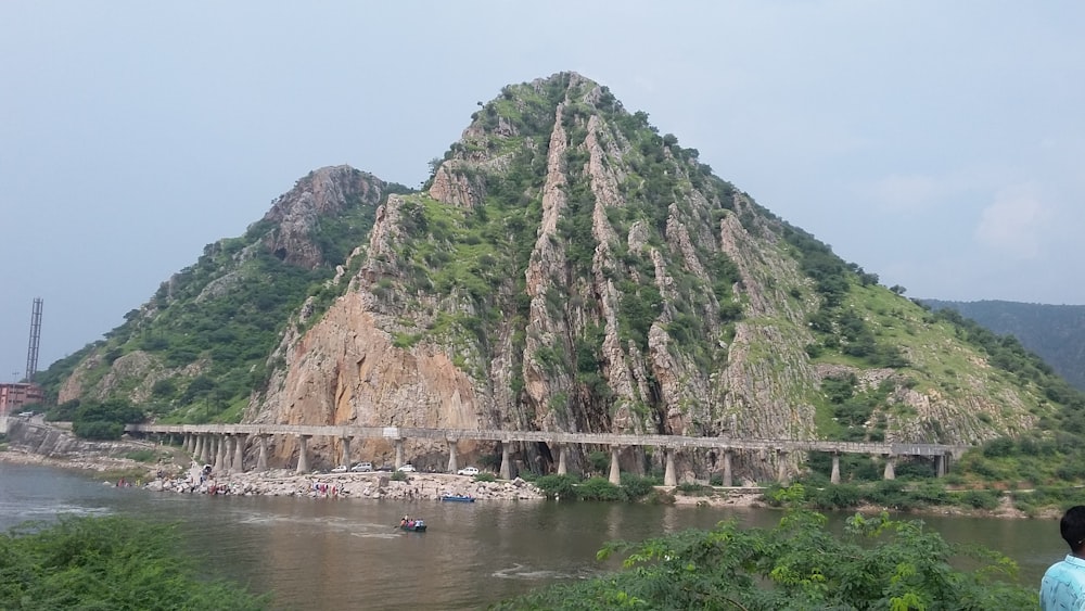 brown and green mountain beside body of water