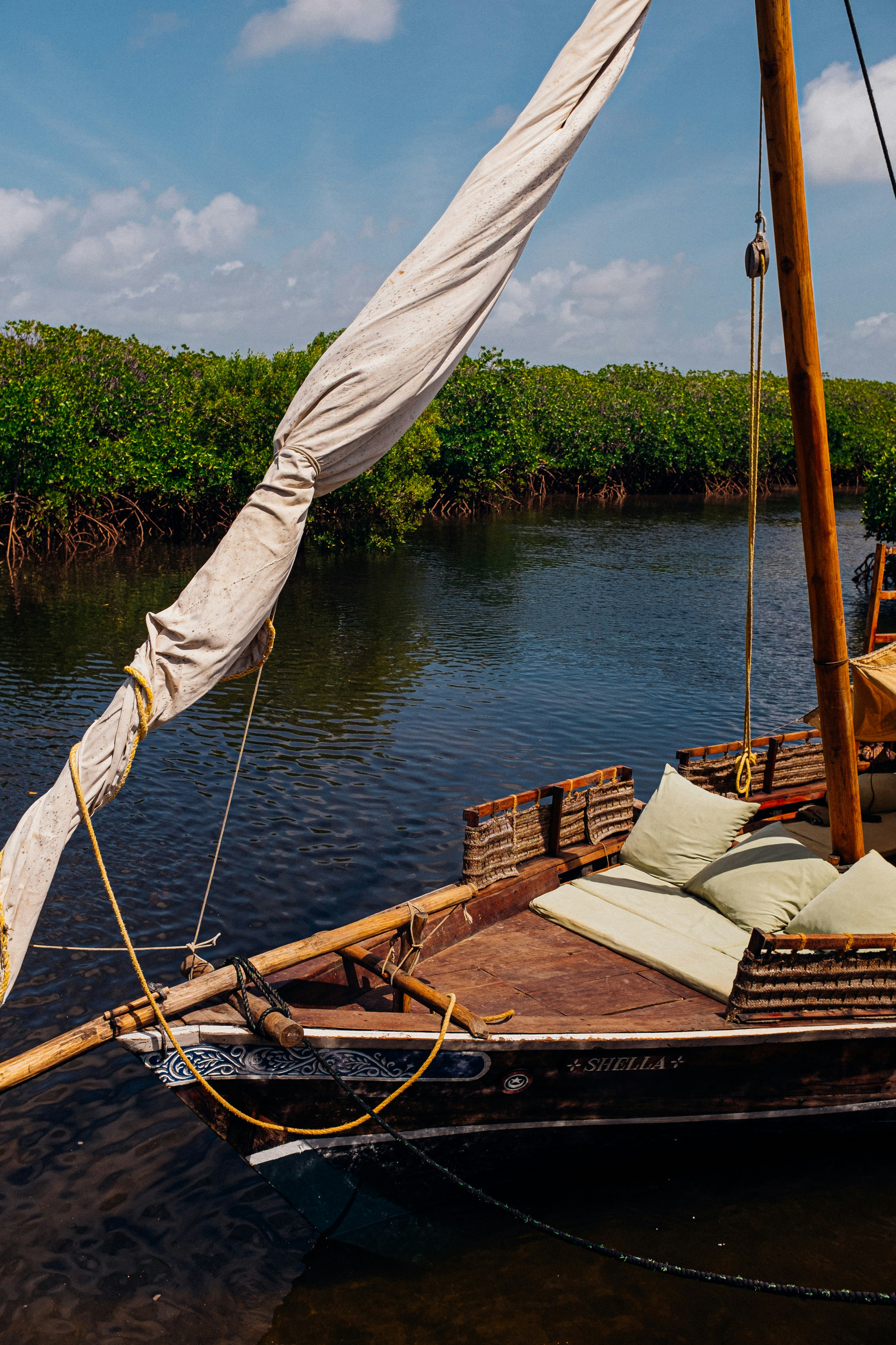 Small wooden boat on calm backwater with green mangroves, golden sunset reflection on water