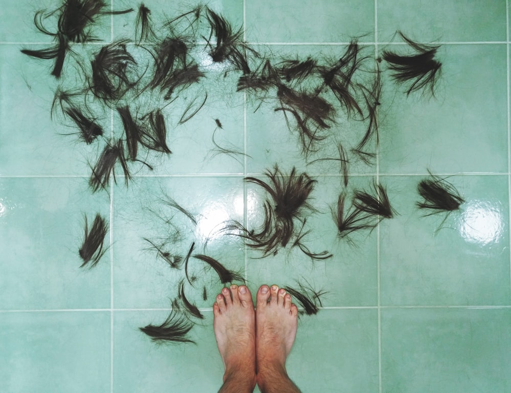 hair on tiled floor near person's feet