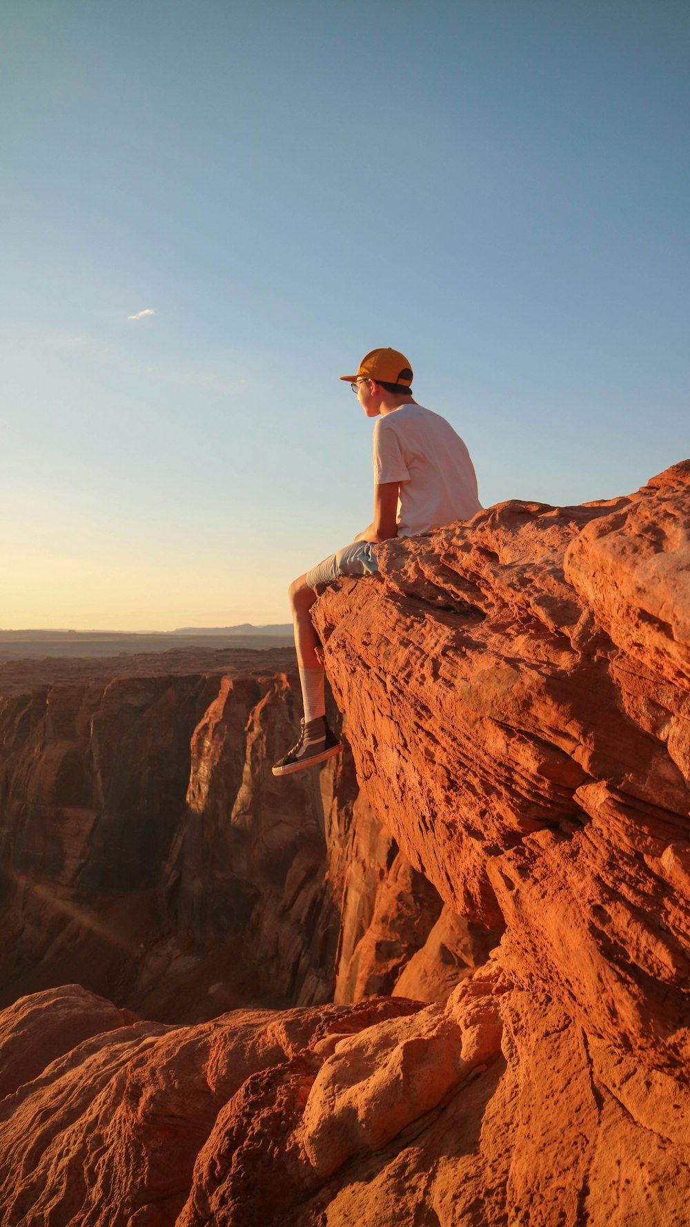 man in white top sitting on cliff