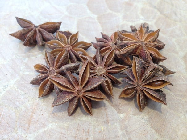 Star anise pods scattered beside a steaming cup of freshly brewed coffee.