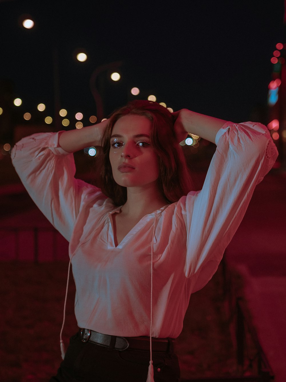 woman wearing white long-sleeved blouse standing and putting both hands on her head