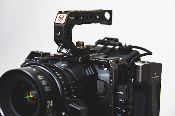 A professional cinema camera with a robust cage and various attachments, including a lens with visible focal length markings, an HDMI port, and a top handle. The setup appears intricate, with metal components and exposed gear, suited for advanced filmmaking.