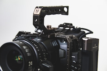 A professional cinema camera with a robust cage and various attachments, including a lens with visible focal length markings, an HDMI port, and a top handle. The setup appears intricate, with metal components and exposed gear, suited for advanced filmmaking.