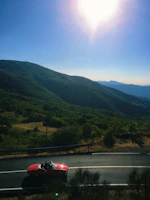 Sunset view over a mountain pass, convertible winding its way through curves edged by pine trees