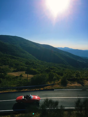 Sunset view over a mountain pass, convertible winding its way through curves edged by pine trees
