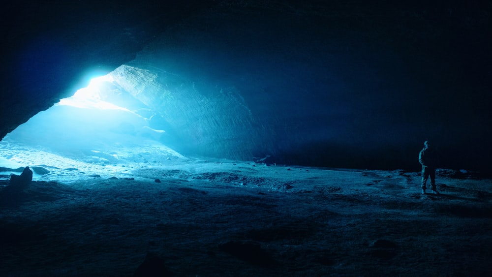 a man standing in a dark cave with a bright light coming from it