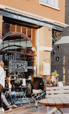 Gezellige borrel in het grandcafé met mensen die lachen en genieten van hapjes en drankjes.
