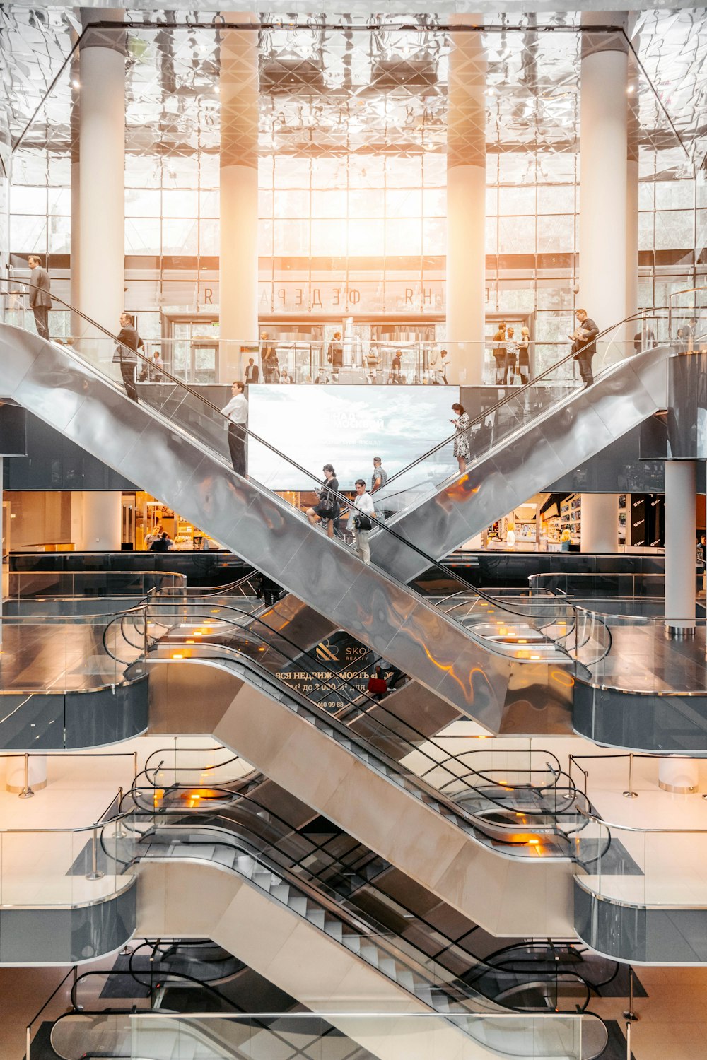 A network of escalators in a large modern building, with people going up and down