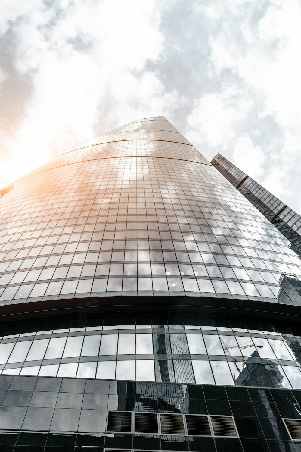 Phot a basso angolo di edificio in vetro sotto il cielo nuvoloso