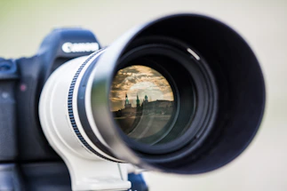 A moody, cinematic close-up of a vintage film camera lens reflecting a dark cityscape at night.