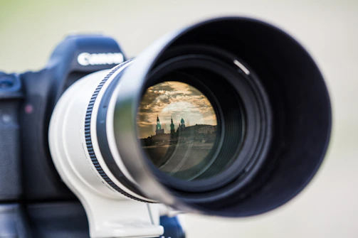 A moody, cinematic close-up of a vintage film camera lens reflecting a dark cityscape at night.