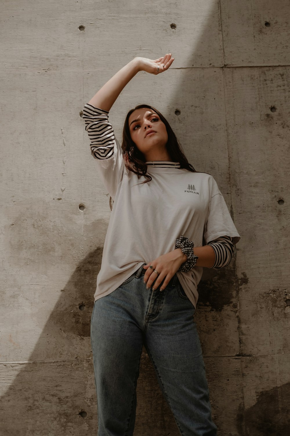 woman in white and black striped top standing near wall