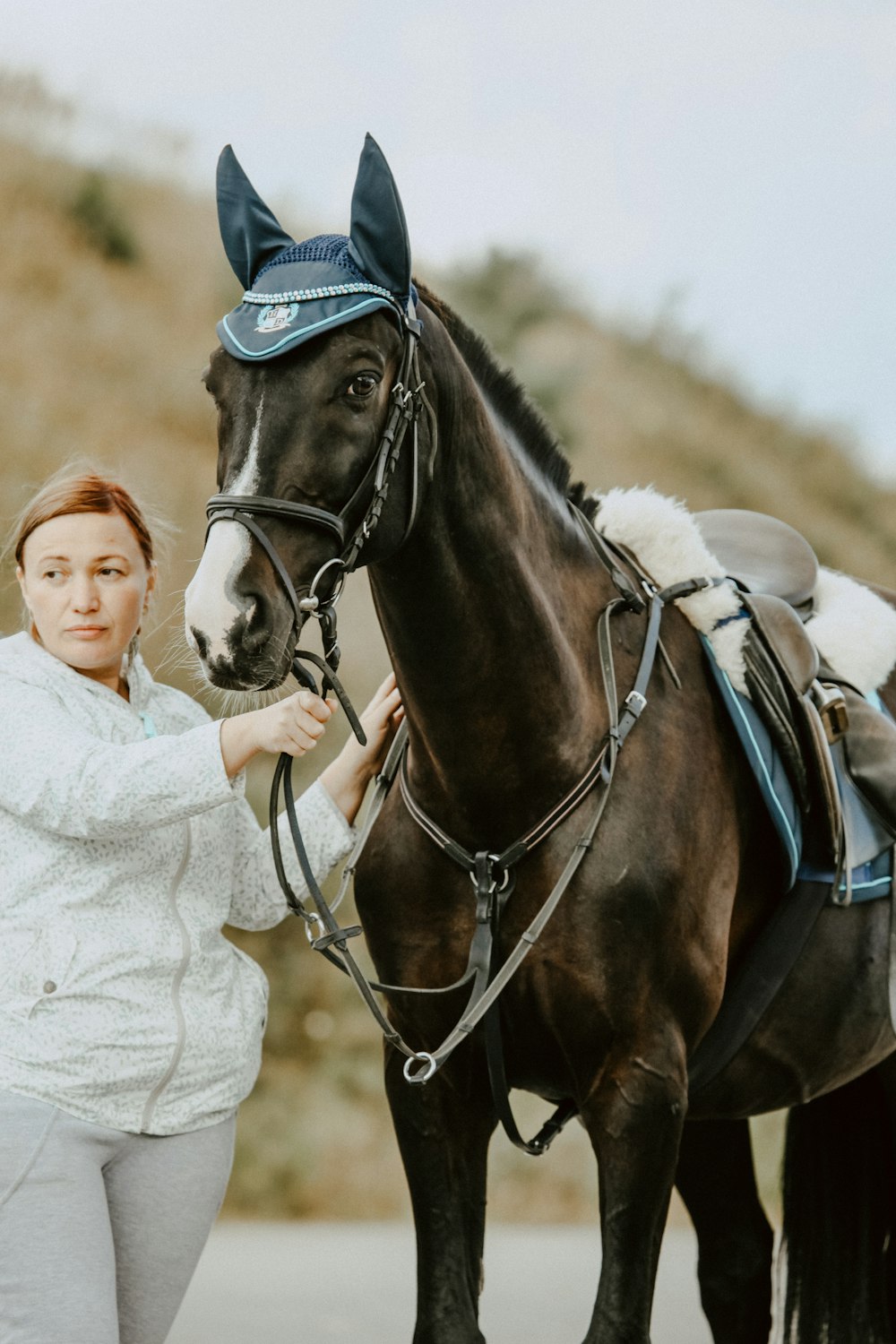 femme portant une veste blanche à côté d’un cheval noir
