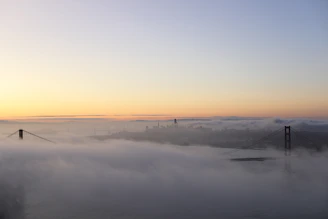 Golden Gate Bridge enveloped in morning fog with soft warm light.