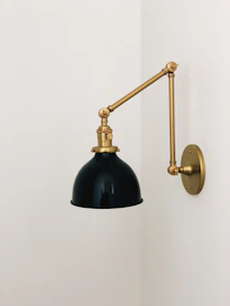 Matte black wall sconce casting adjustable light on a cozy reading nook.