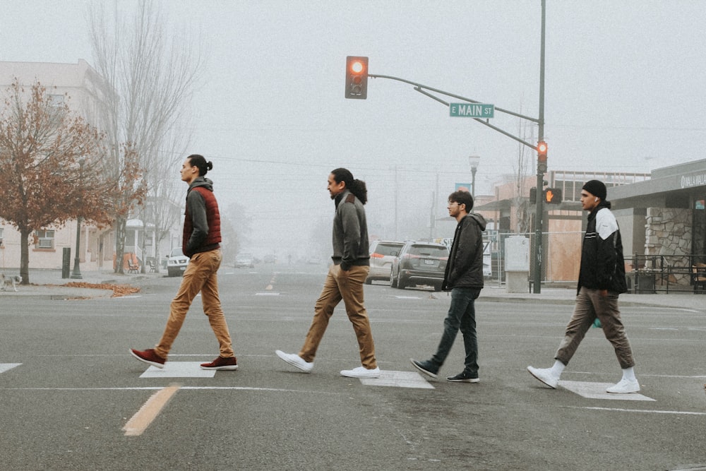 four men crossing street during daytime