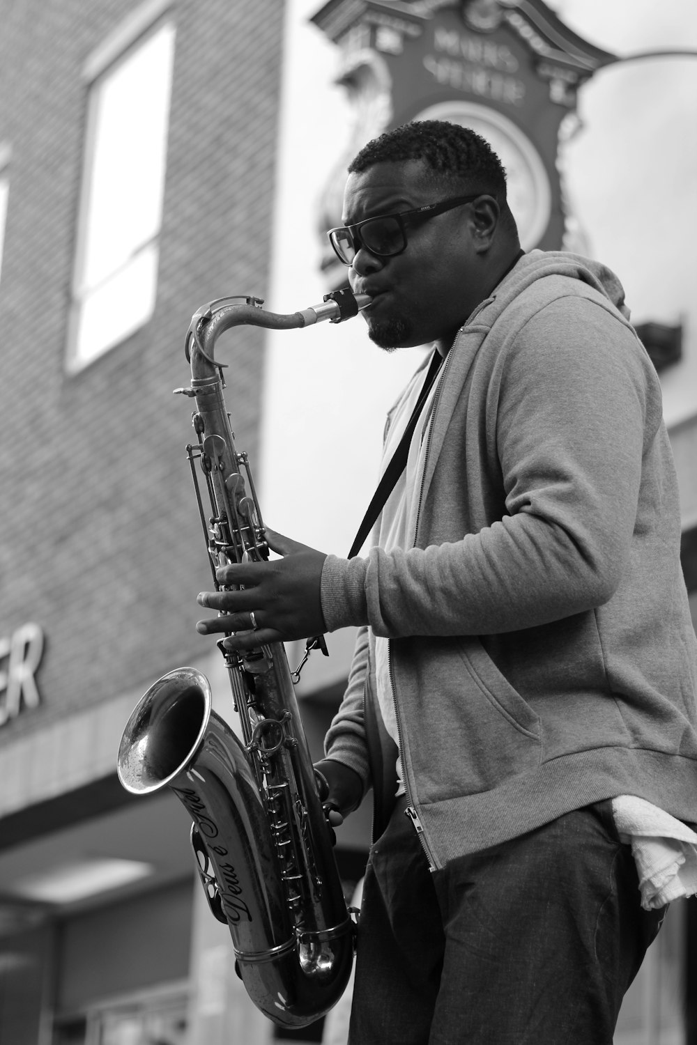 grayscale photo of man playing saxophone