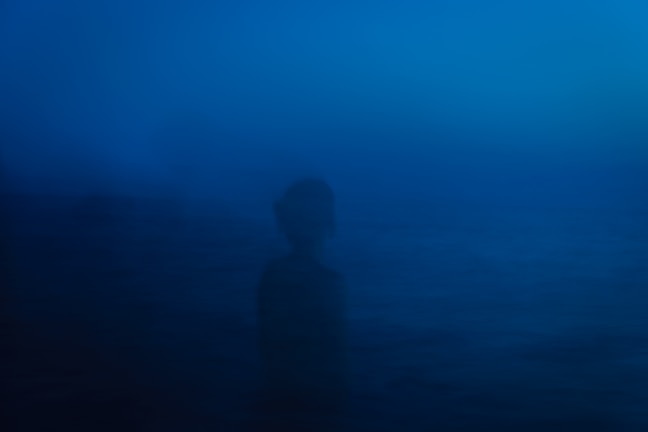 A shadowy figure surrounded by swirling ethereal lights, hinting at a supernatural story.