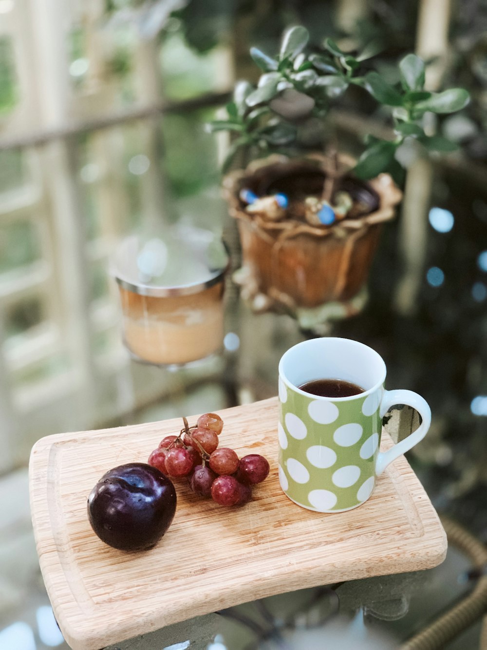 Grüne und weiße Polka-Dots-Keramikbecher und Früchte auf braunem Tablett