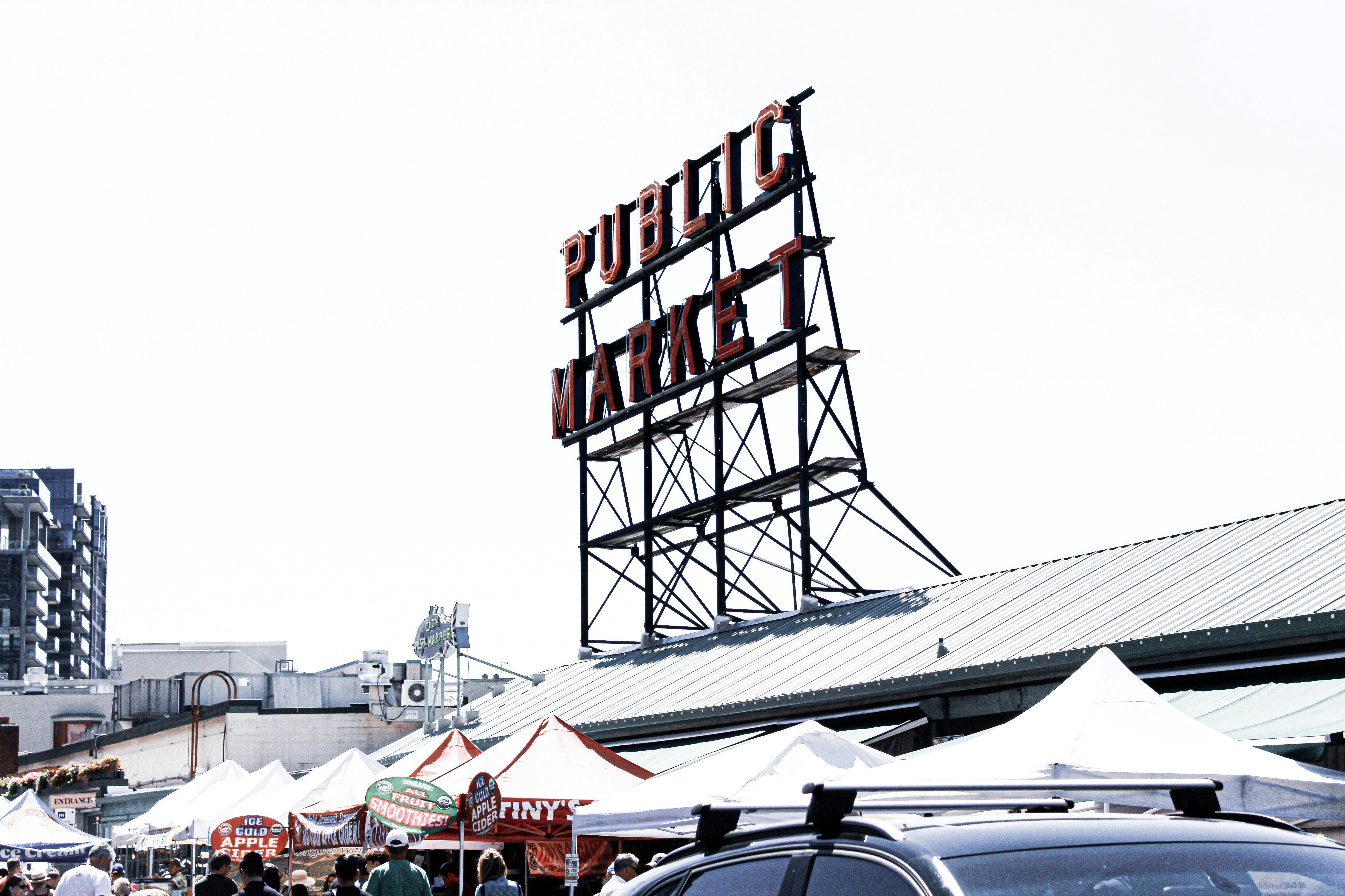 public market signage on top of building roof beside parasols during day