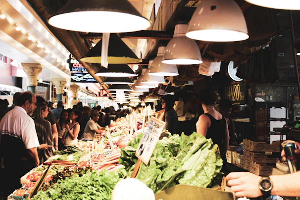 A modern food market stall showcasing fresh produce with customers engaging warmly with vendors.