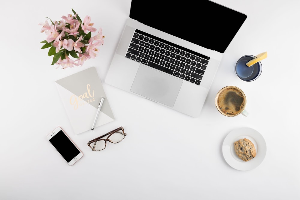 silver laptop and white smartphone on table