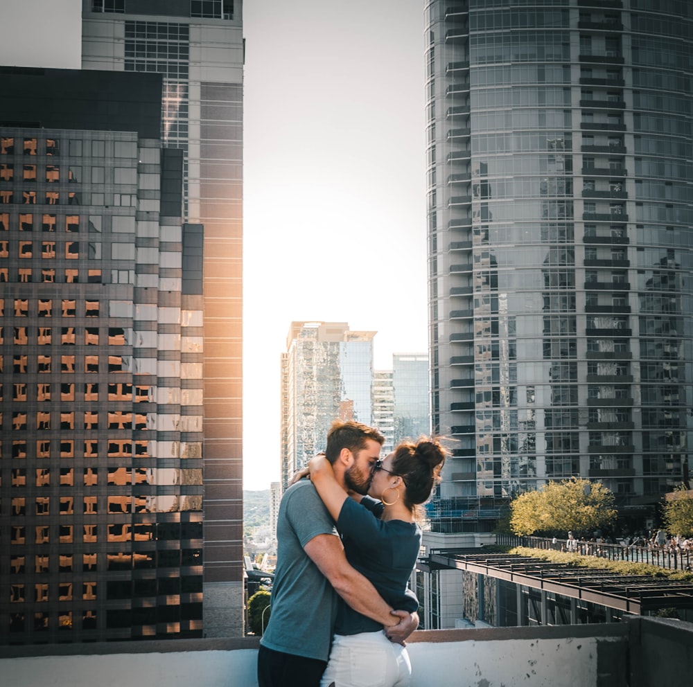 man and woman kissing on top of building