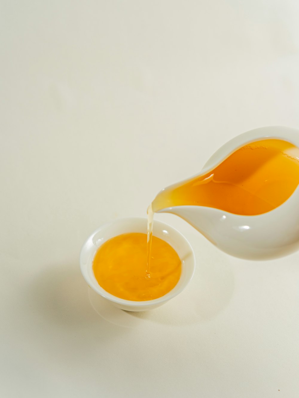 white pot pouring yellow liquid on bowl