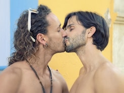 two men with long hair are kissing each other