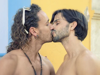 two men with long hair are kissing each other
