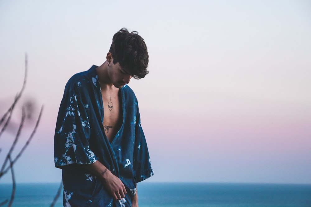 man wearing blue robe standing across body of water