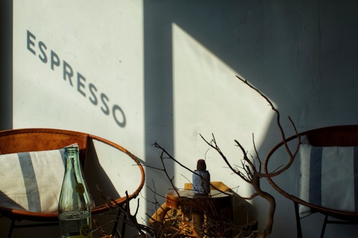 A cozy Italian street café bathed in warm afternoon light, with a traveler enjoying a cup of espresso.