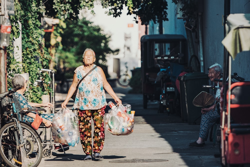 woman carrying two plastic bags of plastic bottles
