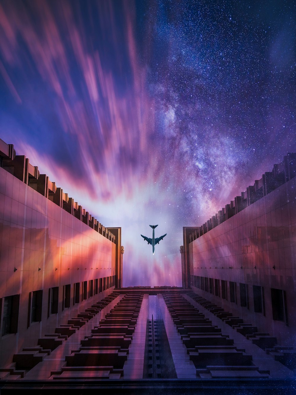 Photographie en contre-plongée d’un avion passant au-dessus d’un bâtiment en béton