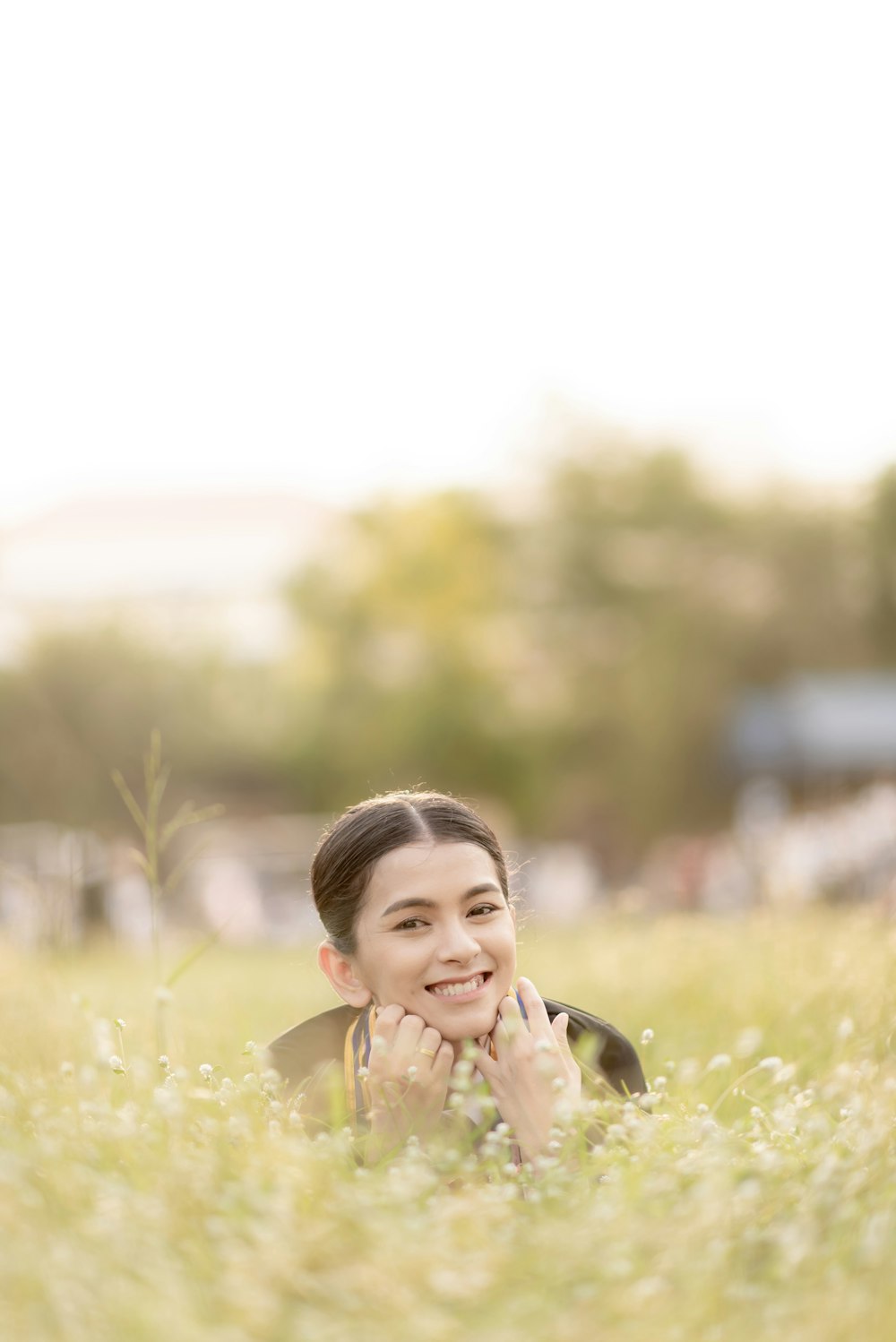 femme souriante à côté d’un champ de fleurs blanches pendant la journée