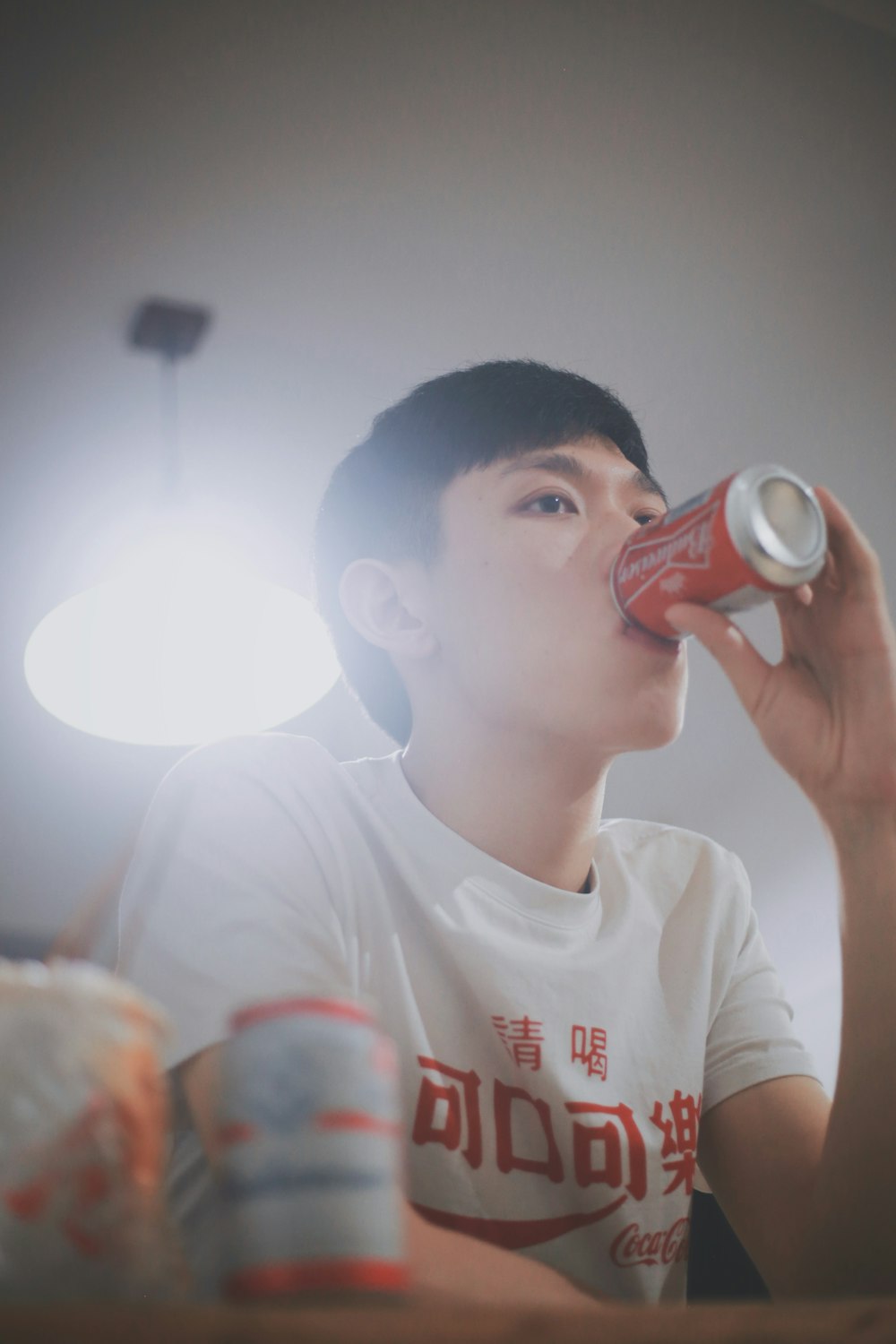 man in white top drinking canned soda