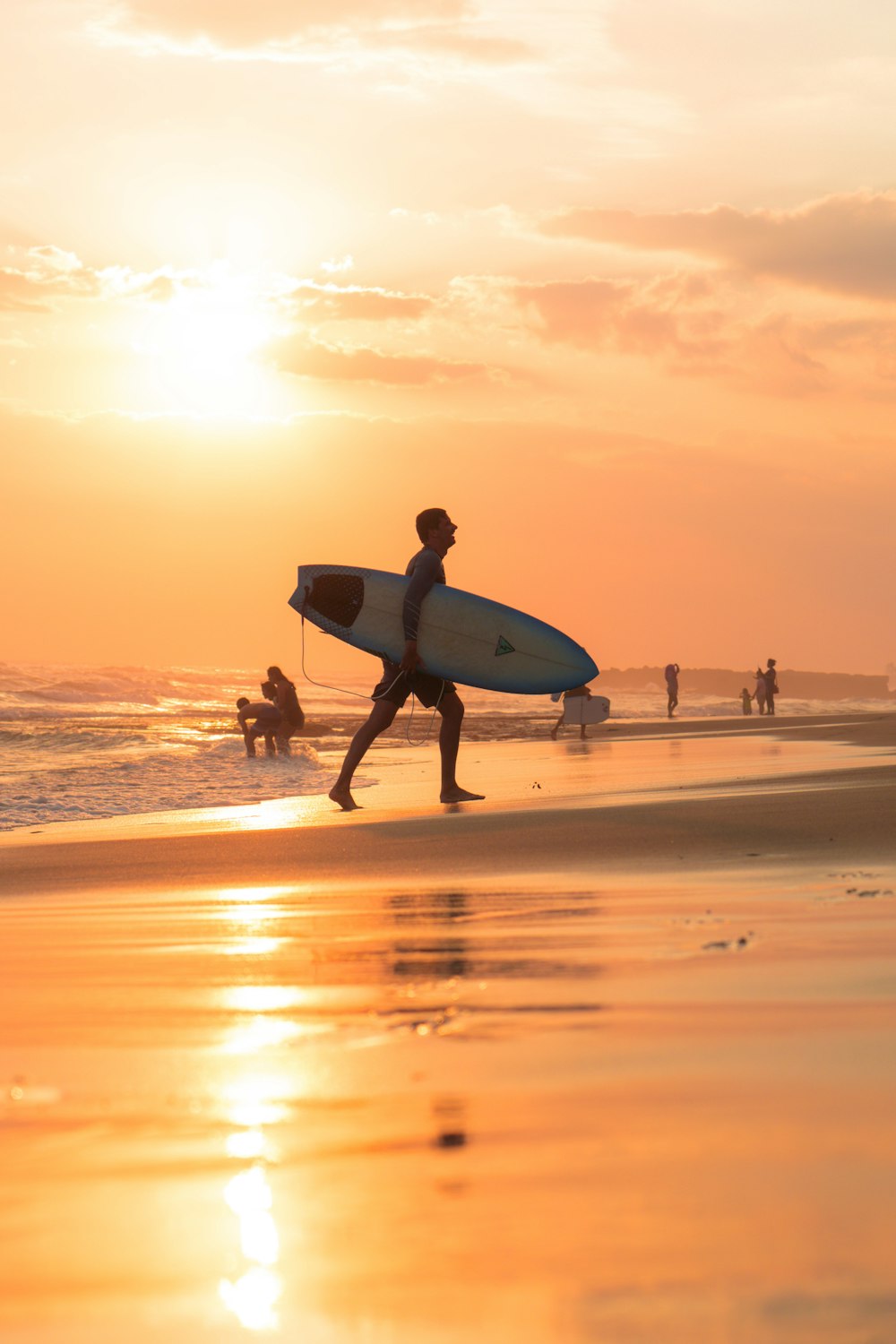 Mann mit Surfbrett während Sonnenuntergang