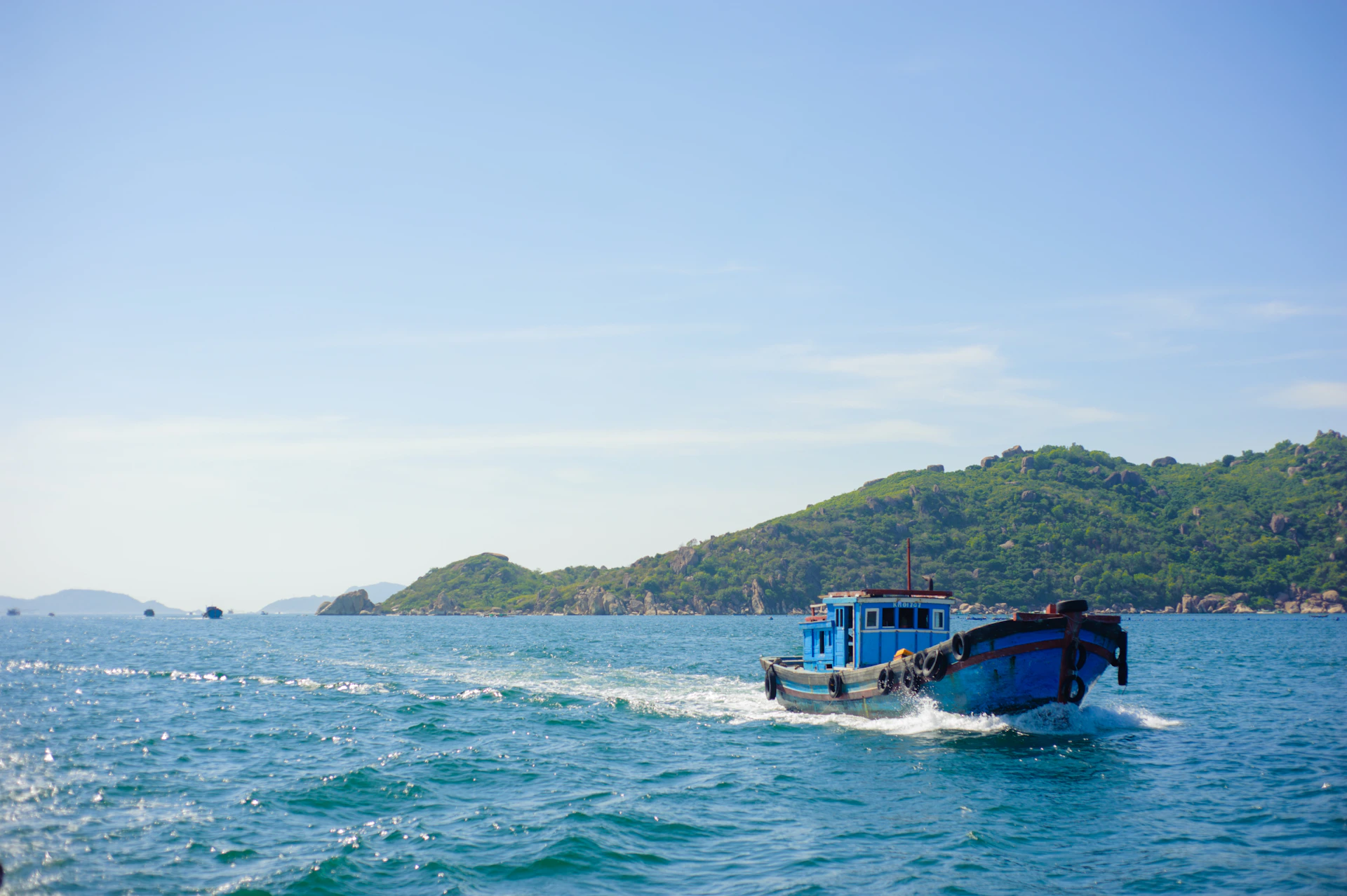 A dynamic scene of the marazul charter boat cutting through the calm waters near Cabo, with anglers readying their spears under a clear blue sky.