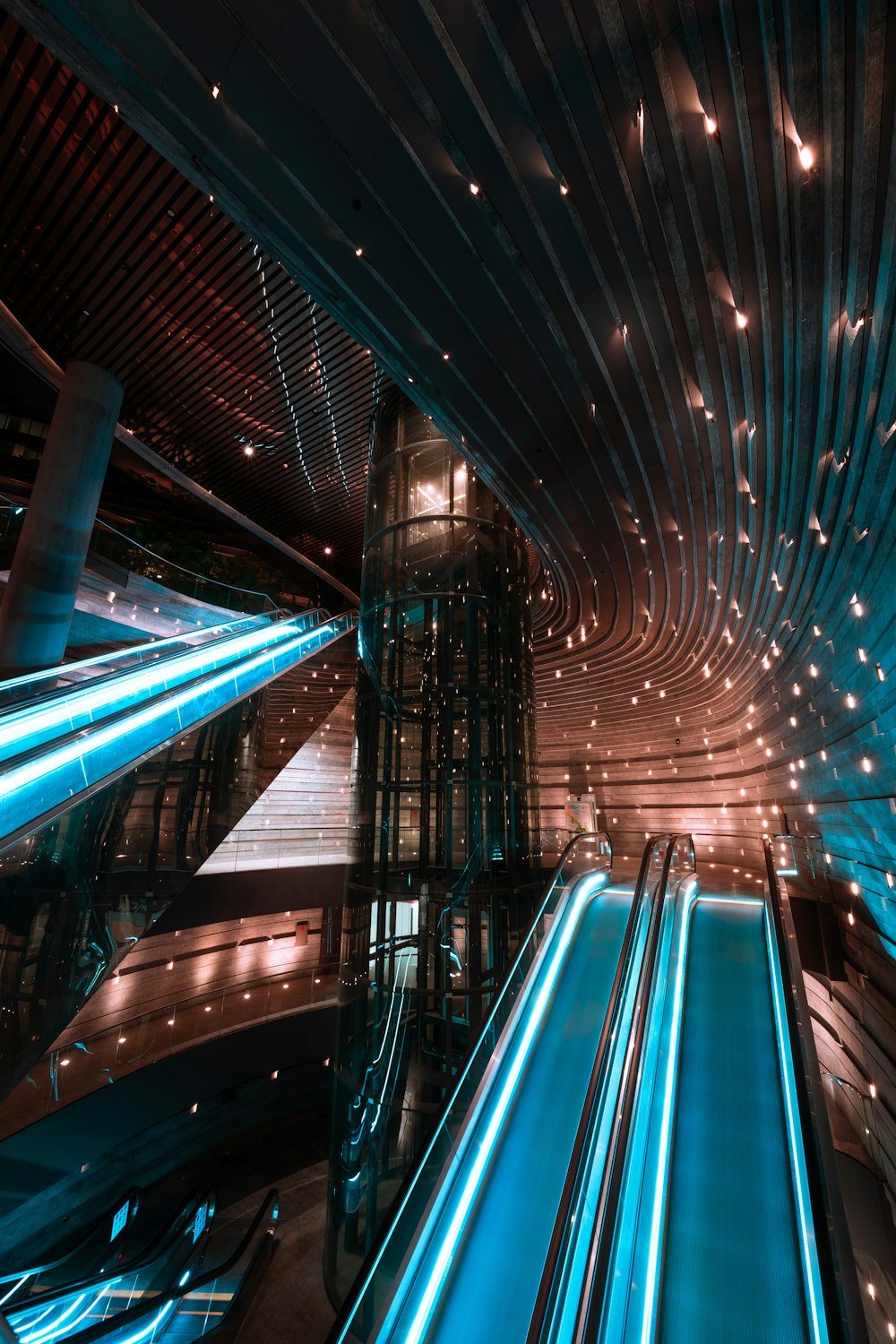 low-angle photography of blue lighted escalators